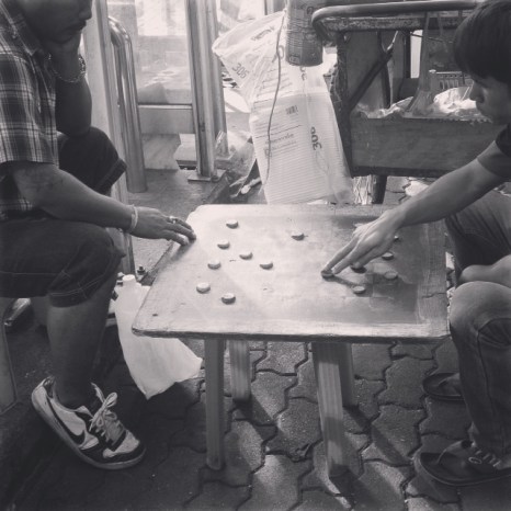 Bottle-cap checkers on the street of Bangkok.